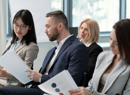 Man in suit at small meeting looking at papers